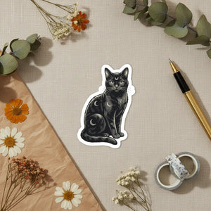 Black cat and moon phase kiss-cut sticker by DipaliZ on a white surface