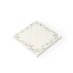 A square cream-colored notepad with a delicate floral wreath border in soft blue and gold, featuring a small gold crescent moon near the bottom left corner, shown on a clean white background.