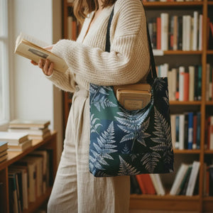 A tote bag with a dark green and navy fern pattern and black shoulder straps, shown against a plain white background.
