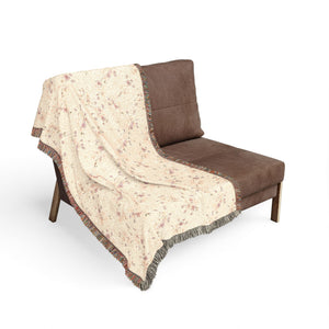 Brown chair with a floral-patterned beige blanket draped over it on a white background