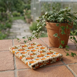Small pumpkins and leafy sprigs in rust on a DipaliZ cotton tablecloth