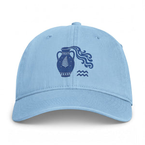 A light blue baseball cap featuring a dark blue embroidered graphic of a vase with flowing lines and wavy patterns on the front panel, set against a plain white background.