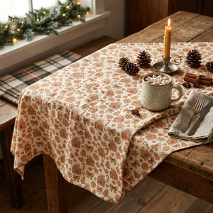 A square sheet of patterned paper featuring a repeating holiday design of gingerbread houses, cookies, stars, and candy canes in warm brown and orange tones on an off-white background.