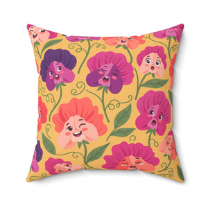 A square throw pillow featuring a retro-style floral pattern with smiling, winking, and surprised flower faces in pink, purple, and orange on a mustard yellow background.