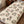 A cream-colored bedding set, including a comforter and matching pillowcases, featuring a repeating pattern of cute cartoon raccoas and red mushrooms on a wooden bed frame.