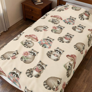 A cream-colored bedding set, including a comforter and matching pillowcases, featuring a repeating pattern of cute cartoon raccoas and red mushrooms on a wooden bed frame.