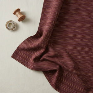 Flat lay of DipaliZ striped maroon combed cotton fabric by the yard