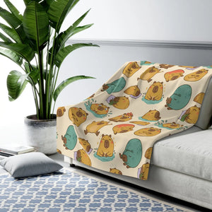 Grass tufts and leaves scattered between capybaras on the DipaliZ blanket design