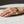 A gold metal cuff bracelet engraved with the words 'find your purpose' in black lettering, worn on a person's wrist resting on a white marble surface.